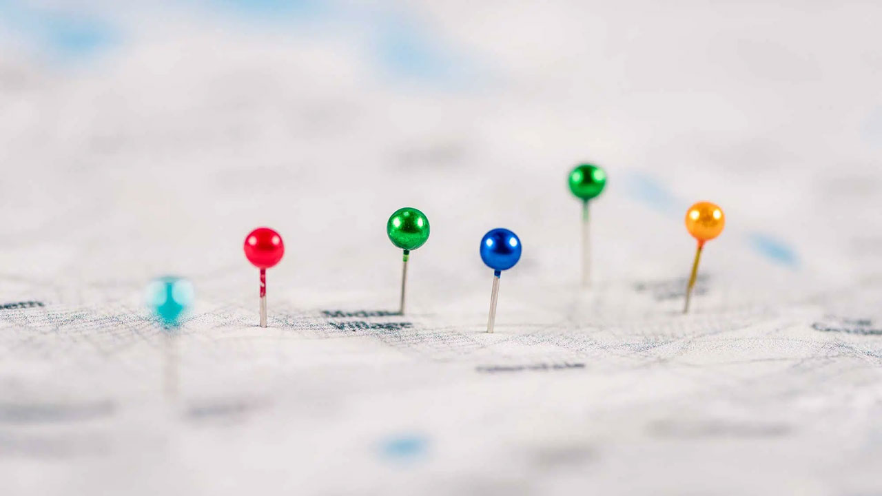 A close-up view of a map with colorful push pins marking different locations