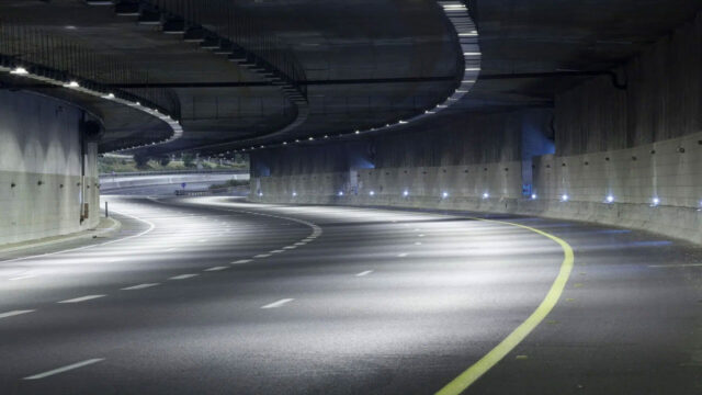 Empty curved highway tunnel with overhead lights and smooth concrete walls