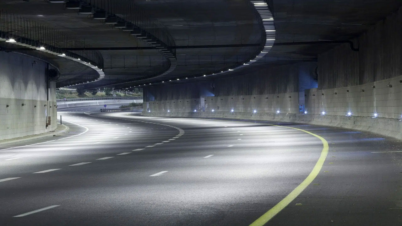Empty curved highway tunnel with overhead lights and smooth concrete walls