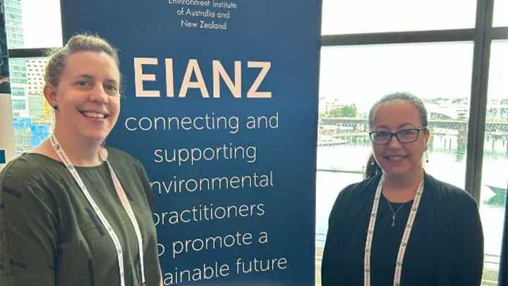Katie Watt and Erin Pears standing in front of a banner for Environment Institute of Australia and New Zealand (EIANZ)