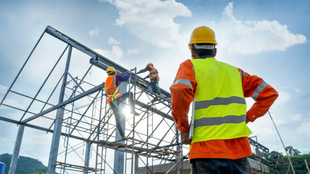 Construction workers in safety gear building metal framework