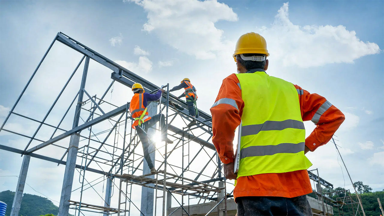 Construction workers in safety gear building metal framework