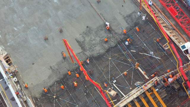 Aerial view of construction workers pouring concrete over steel reinforcement at building site