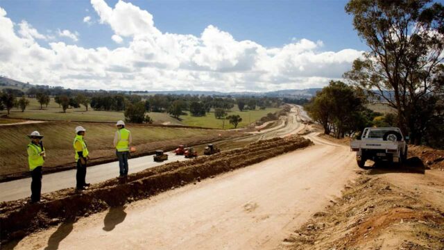 Construction site showing ongoing road and highway development with heavy equipment and cleared land