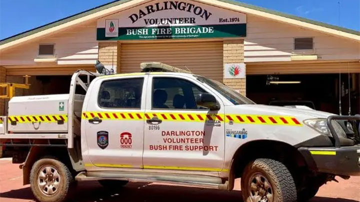 A white utility vehicle parked in front of the Darlington Volunteer Bush Fire Brigade building. The vehicle has yellow and red reflective stripes and text on the side that reads "Darlington Volunteer Bush Fire Support."