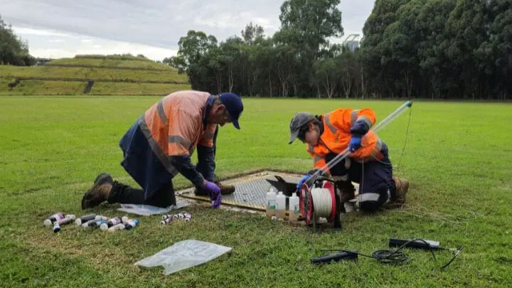 Two people working in orange gear on an environmental monitoring at Olympic Park