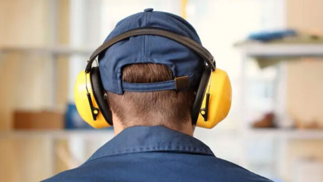 Person wearing blue cap and yellow noise-canceling headphones