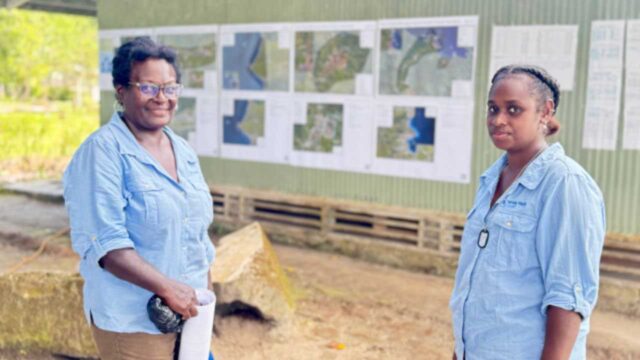 Two people standing in front of visual infographs